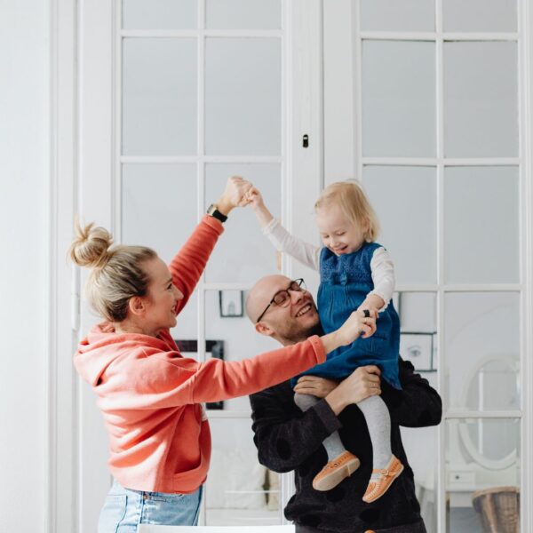 Young family smiling together in a brightly lit room.