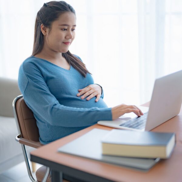 Pregnant woman reading online resources on a laptop.