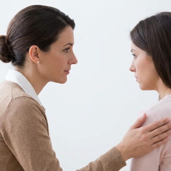 A counselor in profile, listening compassionately to a woman.